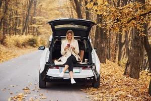 Girl sits on the back of car. Modern brand new automobile in the forest photo