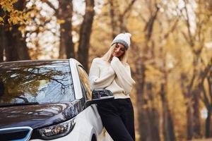 chica tiene viaje de otoño en coche. automóvil nuevo y moderno en el bosque foto