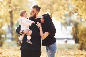 Cheerful family having fun together with their child in beautiful autumn park photo