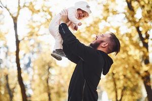 Father in casual clothes with his child is in the beautiful autumn park photo