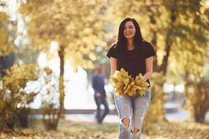 Brunette in casual clothes have fun with leaves in beautiful autumn park photo