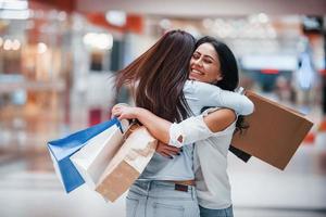 Meeting of two female friends in the mall at weekend shopping time photo