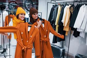 probando gorros y bufandas calientes. dos mujeres jóvenes tienen un día de compras juntas en el supermercado foto