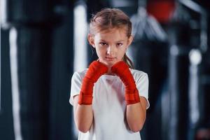 Portrait of young little girl in sportive wear that is in the gym have exercise day. Conception of boxing photo