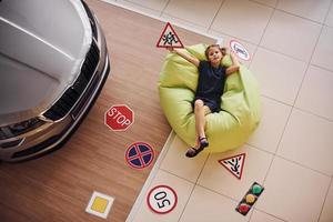 Top view of cute little girl that holds road signs in hands in automobile salon photo