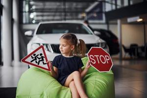 retrato de una linda niña que tiene señales de tráfico en las manos en el salón del automóvil foto