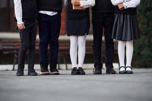 vista de cerca de niños con uniforme escolar que están juntos al aire libre cerca del edificio de educación foto
