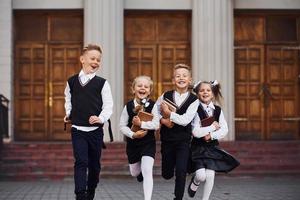 grupo de niños con uniforme escolar que corren juntos al aire libre foto