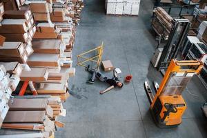 Warehouse worker after an accident in the storage. Man in uniform lying down on the ground photo