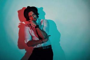 Portrait of young stylish man in formal clothes that stands in neon lights in the studio photo