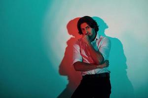 Portrait of young stylish man that stands in neon lights in the studio photo