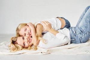 Mother with her daughter together is on the ground in the studio with white background photo