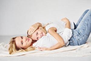 Mother with her daughter together is on the ground in the studio with white background photo