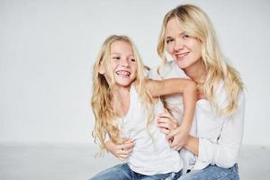 cercanía de la gente. madre con su hija juntas en el estudio con antecedentes blancos foto