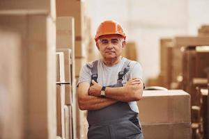 Portrait of senior storage worker in warehouse in uniform and hard hat photo