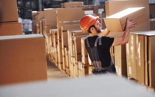 Young storage worker in warehouse in uniform busy with some work photo