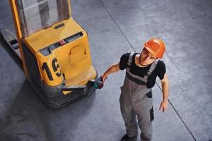 Young male worker in uniform is in the warehouse pushing pallet truck photo