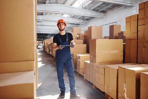 Storage worker in uniform and notepad in hands checks production photo