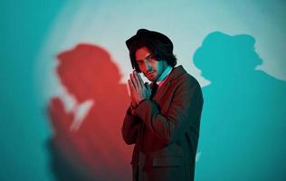 Portrait of young stylish man in hat, suit and tie that stands in neon lights in the studio photo