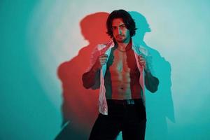 Portrait of young hot man that stands in neon lights in the studio photo