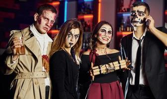 Friends is on the thematic halloween party in scary makeup and costumes have fun and posing for the camera together photo