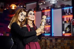 dos amigas están en la fiesta temática de halloween con maquillaje aterrador y disfraces con bomba de tiempo foto