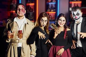 los amigos están en la fiesta temática de halloween con maquillaje y disfraces aterradores, diviértanse y posen juntos para la cámara foto