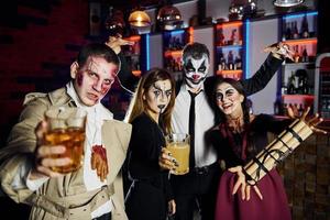 Friends with bomb in hands is on the thematic halloween party in scary makeup and costumes photo