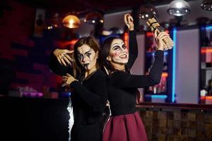 Two female friends is on the thematic halloween party in scary makeup and costumes with time bomb photo