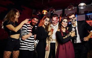 los amigos están en la fiesta temática de halloween con maquillaje y disfraces aterradores, diviértanse y posen juntos para la cámara foto