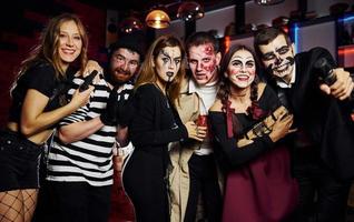 Friends is on the thematic halloween party in scary makeup and costumes have fun and posing for the camera together photo