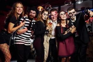 los amigos están en la fiesta temática de halloween con maquillaje y disfraces aterradores, diviértanse y posen juntos para la cámara foto