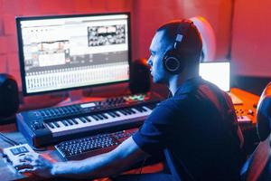 ingeniero de sonido en auriculares trabajando y mezclando música en interiores en el estudio
