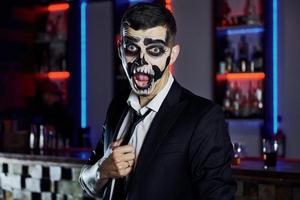 retrato de hombre que está en la fiesta temática de halloween con maquillaje y disfraz de esqueleto aterrador foto