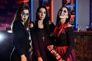 Three female friends is on the thematic halloween party in scary makeup and costumes photo