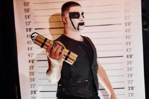 retrato de hombre que está en la fiesta temática de halloween con maquillaje de metal negro aterrador y disfraz con bomba en las manos foto