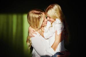 Mother with her daughter together in the studio with green background embracing each other photo