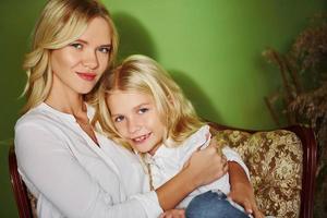 Mother with her daughter together in the studio with green background embracing each other photo