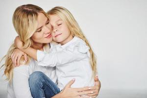 madre con su hija se divierten juntas en el estudio con fondo blanco foto