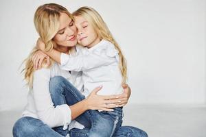 madre con su hija se divierten juntas en el estudio con fondo blanco foto