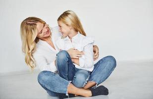 madre con su hija se divierten juntas en el estudio con fondo blanco foto