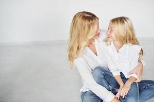 madre con su hija se divierten juntas en el estudio con fondo blanco foto