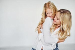 Mother with her daughter have fun together in the studio with white background photo