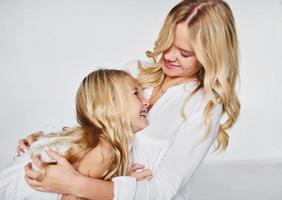 madre con su hija juntas en el estudio con antecedentes blancos foto