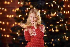 linda niña cerca del árbol de navidad en el interior celebrando el año nuevo foto