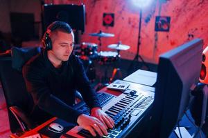 joven ingeniero de sonido trabajando y mezclando música en interiores en el estudio foto