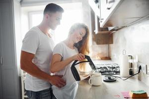 pareja joven en la mañana juntos de pie en la cocina moderna foto