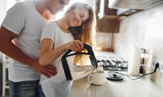 pareja joven en la mañana juntos de pie en la cocina moderna foto