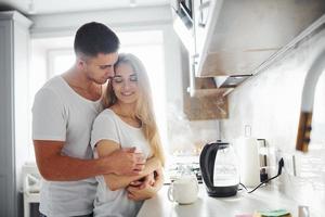 pareja joven en la mañana juntos de pie en la cocina moderna foto