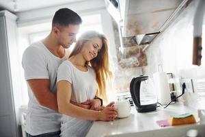 pareja joven en la mañana juntos de pie en la cocina moderna foto